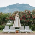 Leżaki ogrodowe na tle gór i kwitnących krzewów na słonecznym tarasie