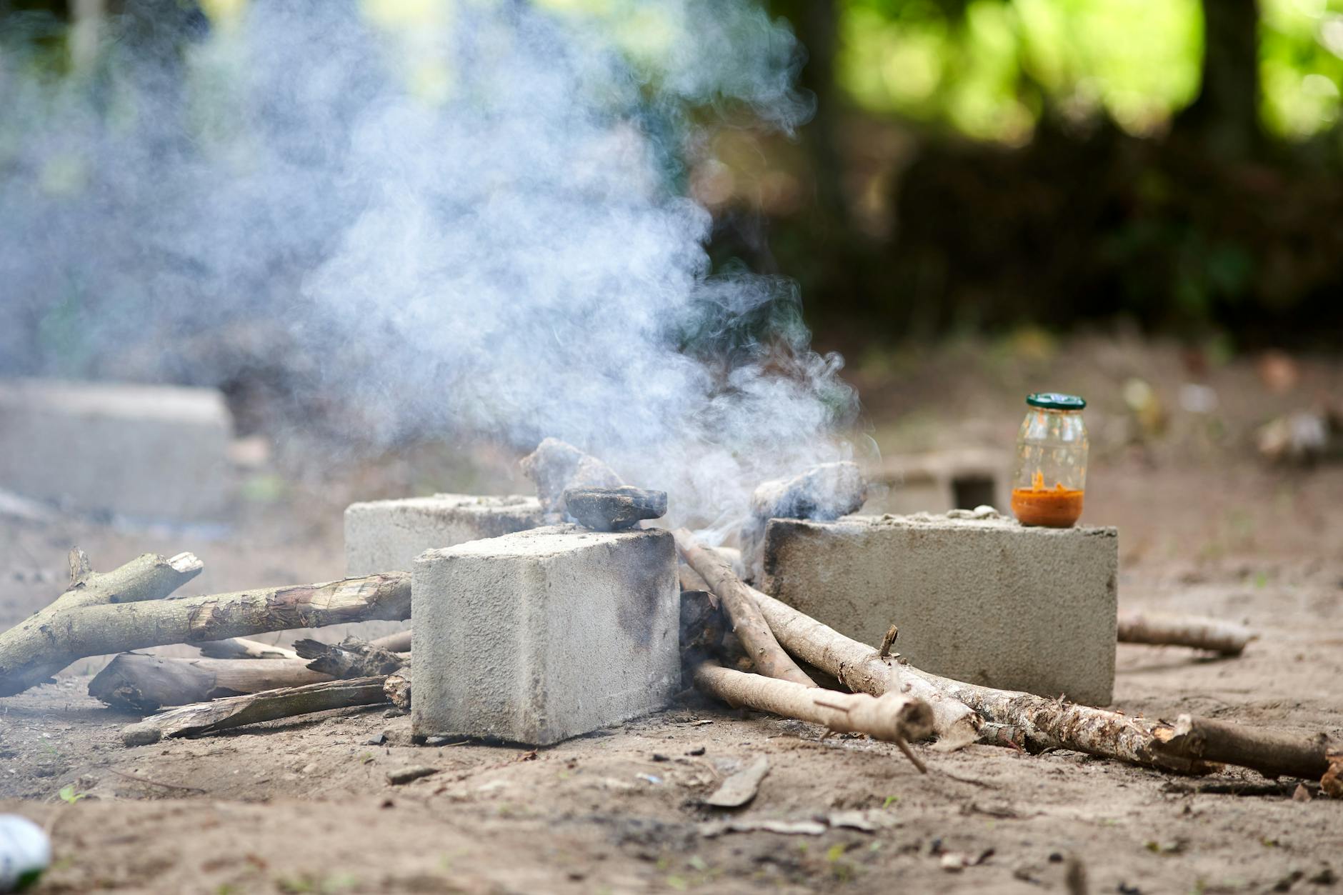Płonące drewno w ognisku ogrodowym obok szklanego słoika