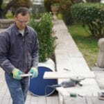 Stolarz w okularach ochronnych pracuje nad projektem drewnianym w ogrodzie