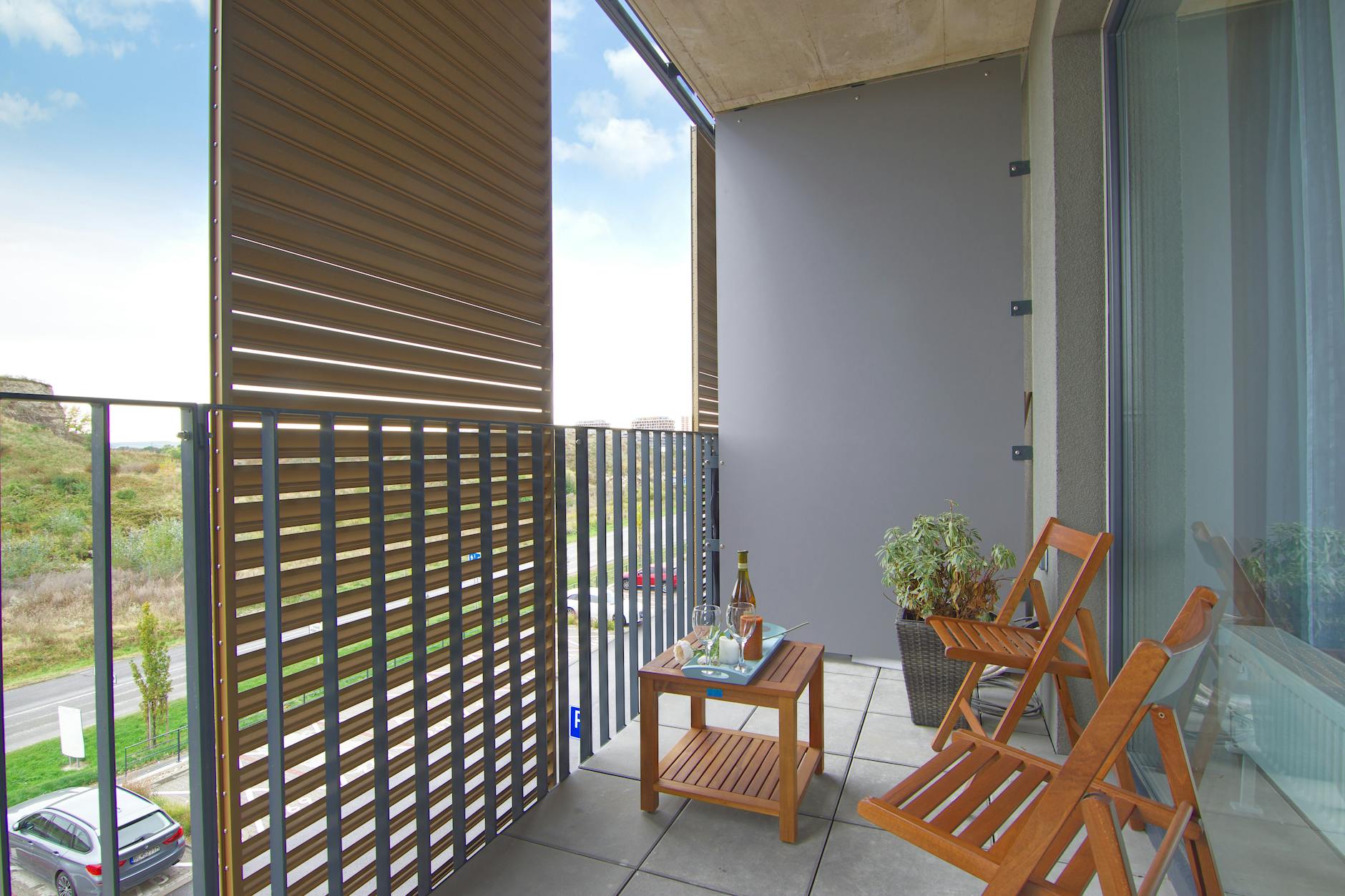 Nowoczesny balkon z drewnianymi krzesłami, stołem i szklaną balustradą