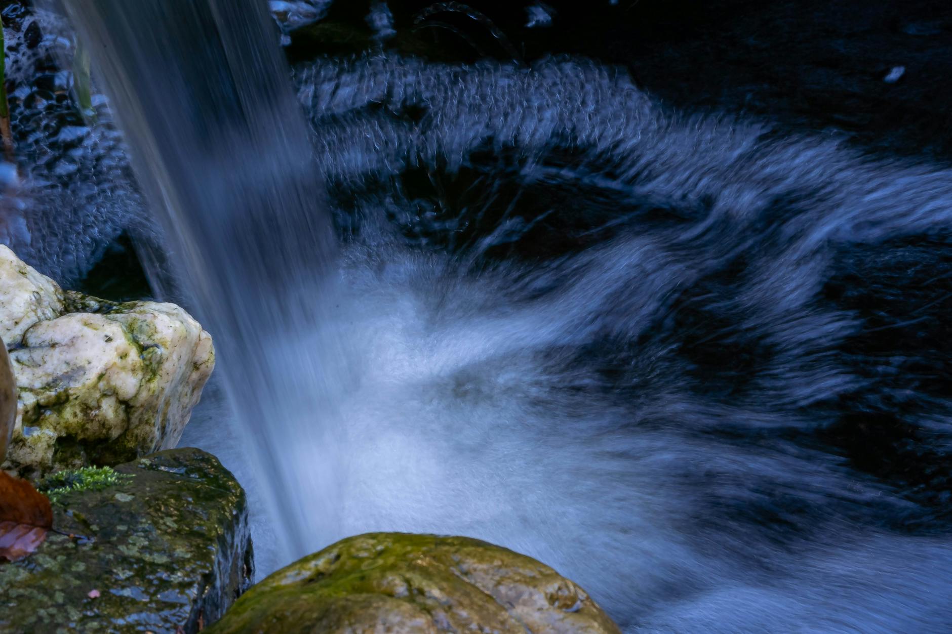Zbliżenie wodospadu w ogrodowym strumieniu spływającego po skałach